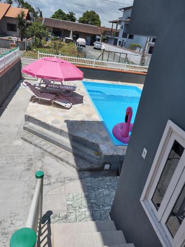 南圣弗朗西斯科Apto com piscina 3 quartos 500m do mar praia Ubatuba的游泳池配有粉红色遮阳伞和粉红色天鹅