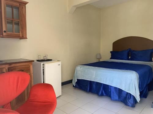 尼格瑞尔Relax in Jamaica - Enjoy 7 Miles of White Sand Beach! villa的一间卧室配有一张床和一张红色椅子