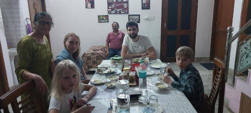 阿尔瓦尔Travel curiosity Homestay的坐在餐桌旁吃食物的家庭