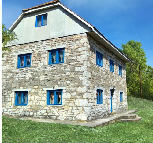 普列夫利亚Etno kuća Krvavac的山丘上带蓝色窗户的石头房子