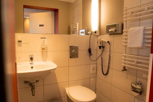 罗斯托克体育论坛酒店的一间带水槽、卫生间和镜子的浴室