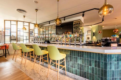 萨顿伦敦萨顿假日酒店的一间设有绿色椅子的餐厅酒吧