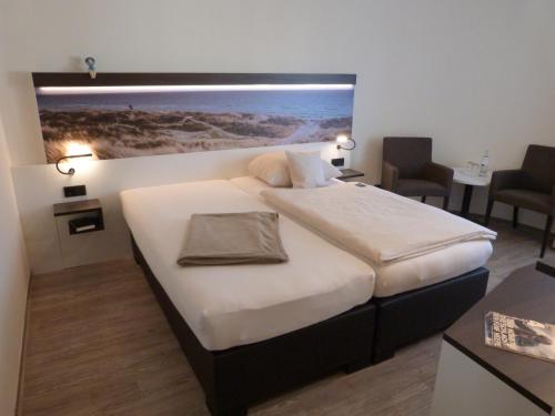 威廉港安科广场加尼酒店的卧室配有一张大床,墙上挂有绘画作品
