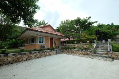 Ban Muang Ton Mamuang三M山区度假酒店的一座石墙和车道的房子