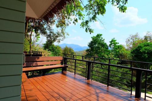 Ban Muang Ton Mamuang三M山区度假酒店的阳台上的木甲板上设有长凳
