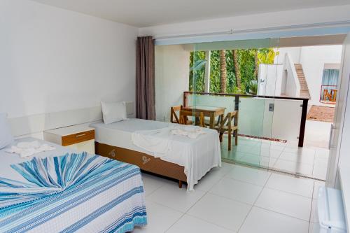 莫罗圣保罗Brisa do Mar Praia Hotel的一间带两张床和一张桌子的卧室以及一个阳台