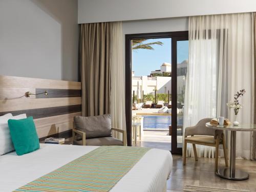 赫尔格达Ancient Sands Golf Resort and Residences的酒店客房设有一张床铺、一张桌子和一个庭院。