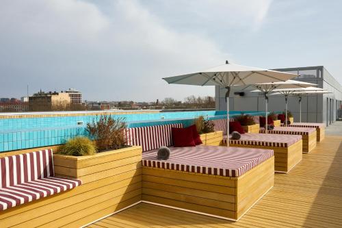 图卢兹The Social Hub Toulouse的一个带长椅和遮阳伞的甲板和一个游泳池