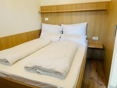 梅拉诺比奇勒公寓酒店的一张带白色床单和枕头的床