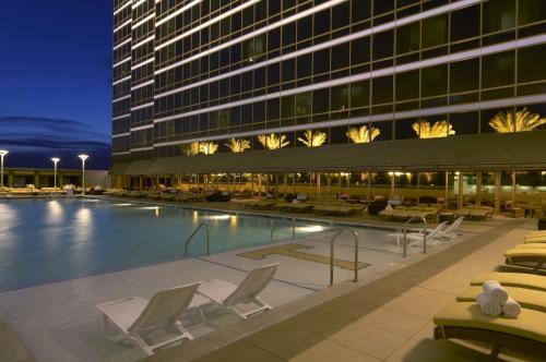 拉斯维加斯Trump International Hotel Las Vegas的酒店游泳池设有躺椅,酒店大楼