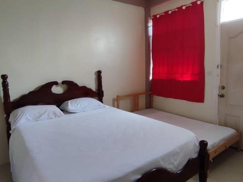 PortsmouthIso’s Vacation Rental Apartment #8的一间卧室设有两张床和一个带红色窗帘的窗户。