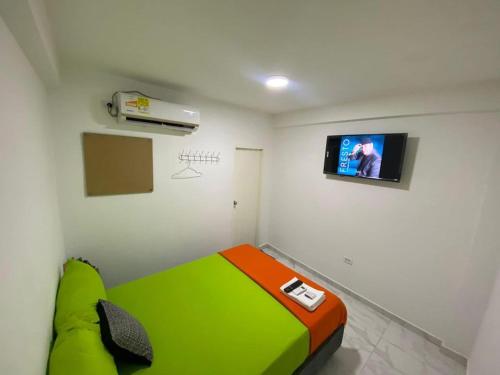 里奥阿查Hotel Aventura Riohacha的一间设有绿色床和墙上电视的客房