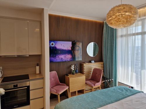 贝尔格莱德Beograd na vodi - BW AURORA LUXURY的一间卧室配有一张床,厨房配有粉红色的椅子