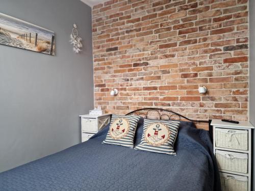 加茨比亚格拉Amko Style Apartament Nord 6 Willa Nord的一间卧室设有砖墙和一张带枕头的床
