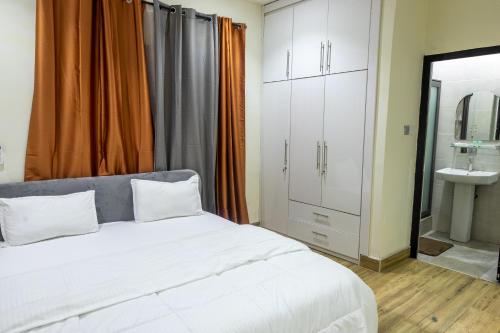 阿克拉Cloud9 Luxury Apartments的卧室配有白色的床和水槽