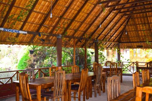 尼拉瓦利Mithra Paradise Beach Hotel的木屋顶下的木桌和椅子