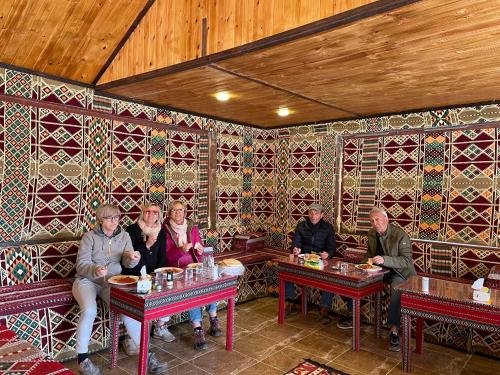 瓦迪拉姆Desert Jewel Camp的一群坐在餐厅桌子上的人