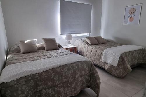 La MercedesElegante y fino departamento a estrenar!的一间卧室设有两张床和窗户。