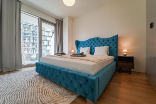 维也纳The View 01.10 - Quartier Belvedere的一张蓝色的床,位于带大窗户的房间里