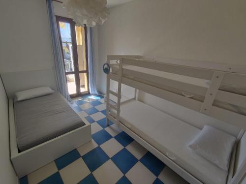 锡罗洛Appartamento L'Azalea - a due passi da Numana con grande terrazzo e piscina condominiale stagionale的客房设有两张双层床和一张可拼接的地板。