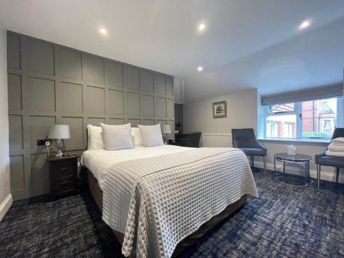 沃金厄姆Cantley House Hotel - Wokingham的一间卧室配有一张大床和一把椅子
