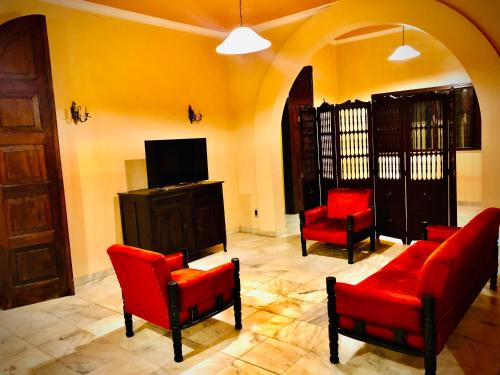 科伦巴Dom Alberto Hostel的客厅配有红色椅子和电视