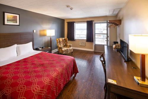 米拉米契Econo Lodge Miramichi的酒店客房设有红色的床和客厅。