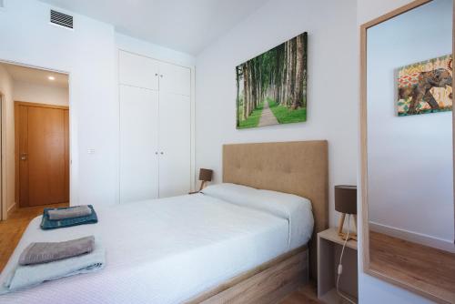 塞维利亚Apartamento estelar con piscina y garaje nervión的白色卧室配有床和镜子
