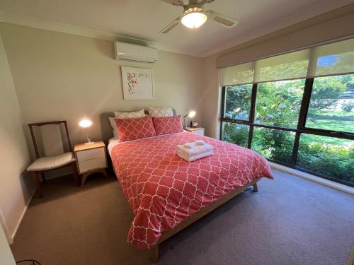 布赖特Magnolia on Toorak的一间卧室配有一张带粉红色棉被的床和窗户