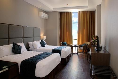 马尼拉Golden Phoenix Hotel - Manila的酒店客房设有两张床和窗户。