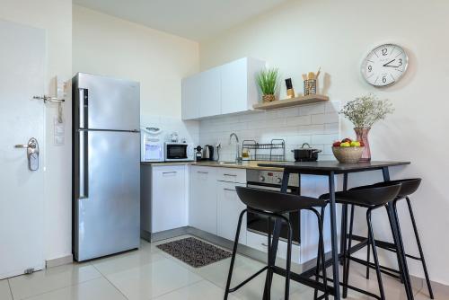埃拉特Melony Apartments Yam Suf Street的厨房配有冰箱和带凳子的桌子