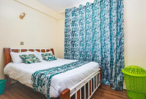 内罗毕Tropical themed 3BR and DSQ Apartment的一间卧室配有一张蓝色窗帘的床