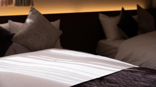 富士河口湖HOTORI no HOTEL BAN的一张带白色床单和枕头的床