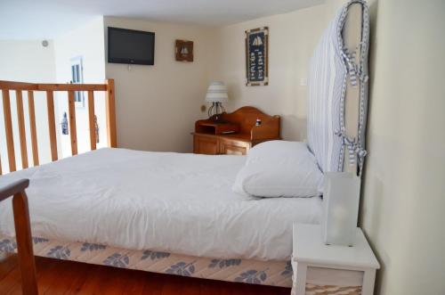 滨海布洛涅Petite Maison de plage的卧室配有白色的床和电视。