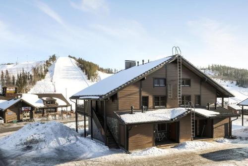 耶姆赛Himos Mökki superior - Chalet Cottage superior ski-in-ski-out的小木屋,屋顶上积雪,滑雪场