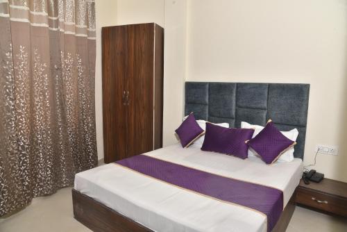 阿姆利则APEX HOTEL的一间卧室配有一张带紫色枕头的大床
