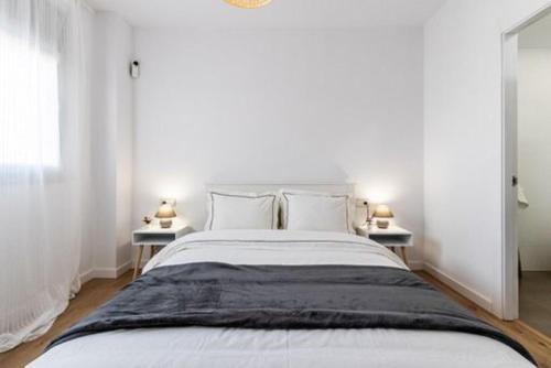 特拉萨Acojedor y exclusivo loft by Lofties的白色卧室配有一张大床和两张桌子