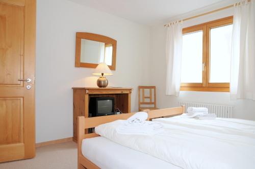 贝特默阿尔卑Ambiente Bettmeralp | A10的一间卧室设有两张床、镜子和电视