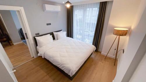 安塔利亚A suites的一间卧室配有一张带白色床单和一盏灯的床。