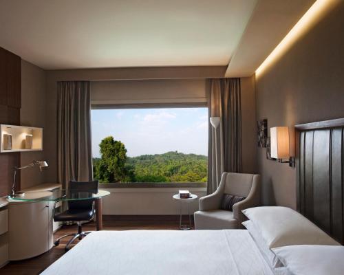 新德里新德里凯悦酒店 的配有一张床、一张书桌和一扇窗户的酒店客房