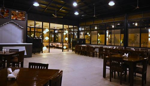 瓜廖尔Shubhim Hotel & Resort MIDWAY TREAT MPT FRANCHISE的用餐室设有桌椅和窗户。