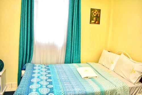 基苏木Classic Studio Milimani - Wi-Fi and Parking的一间卧室配有一张带蓝色窗帘的床和一扇窗户