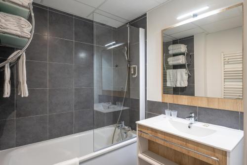 安锡Apparthotel Privilodges Le Royal的一间带水槽、浴缸和镜子的浴室