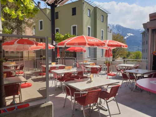 戈尔多拉Ristorante Gordolese con alloggio的一个带桌椅和红伞的庭院