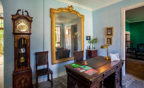 辛特拉辛特拉宫精品住宿加早餐旅馆的配有书桌、镜子和祖父钟的房间