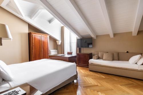 的里雅斯特康堤内塔雷酒店的卧室配有白色的床和沙发