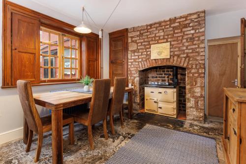 利物浦Air Host and Stay - Anfield cottage, 2 bedroom 2 bathroom的一间带桌子和砖砌壁炉的用餐室