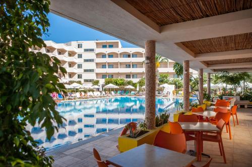 伊利索斯IALYSSOS BAY HOTEL的一个带游泳池和桌椅的度假酒店
