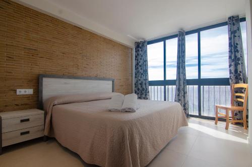 卡尔佩Apartamentos Colón - Grupo Antonio Perles的一间卧室设有一张床和一个大窗户