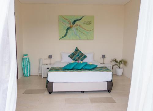 龙目岛库塔Villa Atas Pelangi的白色卧室配有蓝色枕头的床
